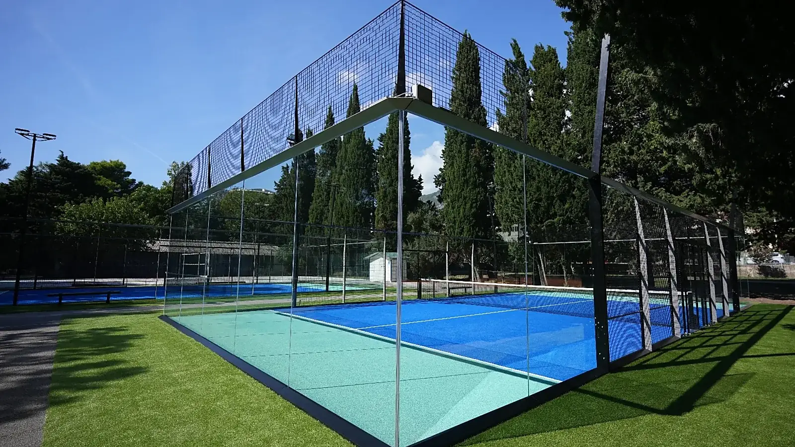Campo da padel panoramico con pareti in vetro e prato sintetico