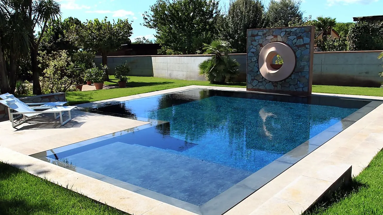 Piscina a sfioro in giardino con scultura